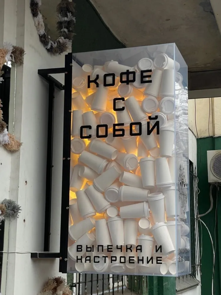 Вывеска «Кофе с собой» из стаканчиков за стеклом
