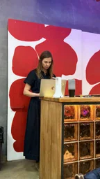 Человек за ноутбуком у деревянной стойки на фоне красно-белой стены
