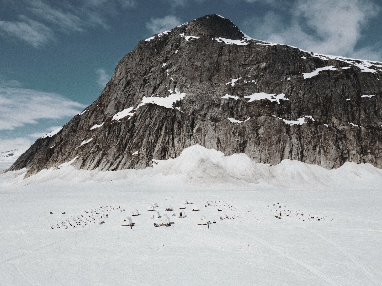 Two trekkers pulling sleds through deep snow toward a high, snow-covered peak