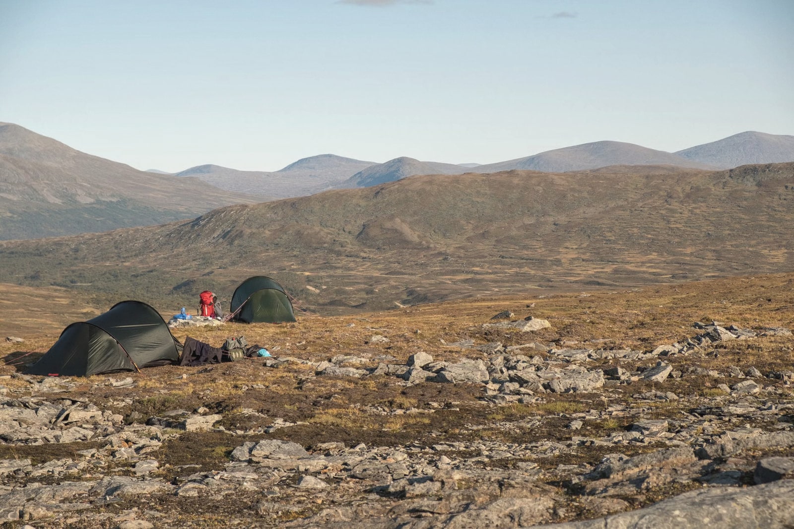 Two tents pitched on open tundra with layered hills in the distance