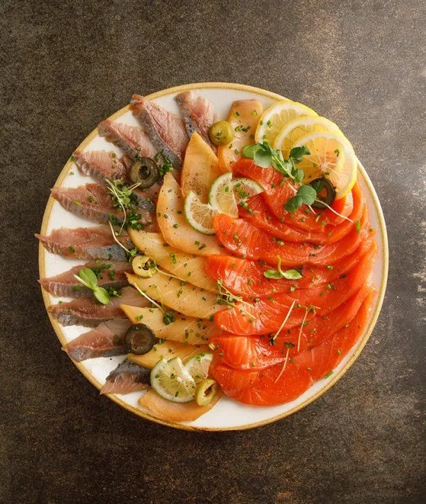 Блюдо с копчёной рыбой, лимоном и оливками